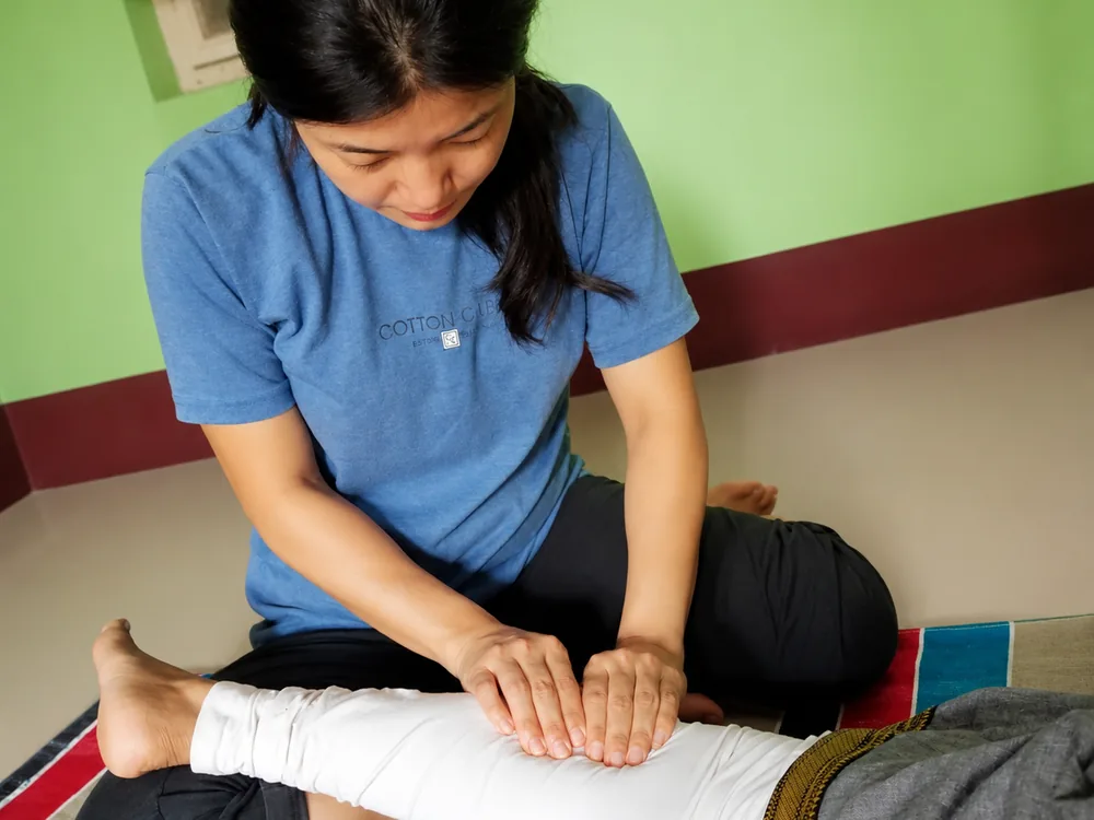 Student practicing Thai massage leg pressure technique at Nirvana School of ThaiMassage and Yoga in Gaya